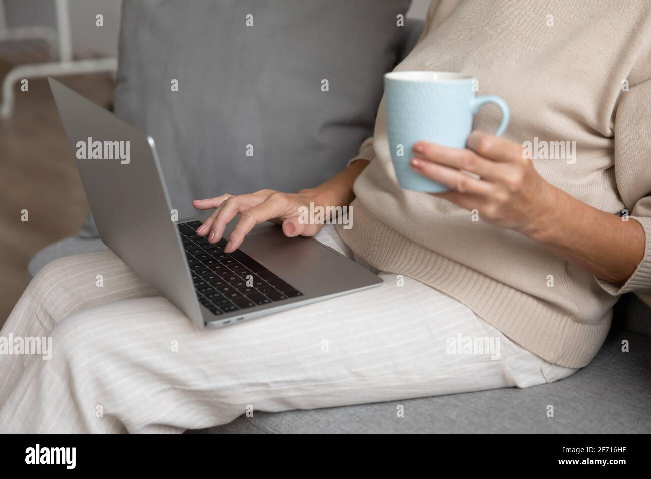 Mature woman using laptop at home, sitting on couch Stock Photo