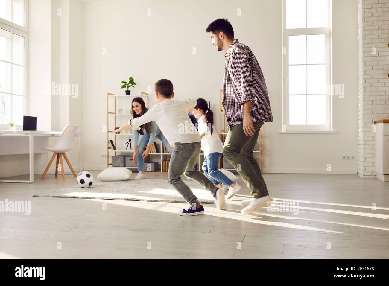 Parents and children spending leisure time together play football at home Stock Photo