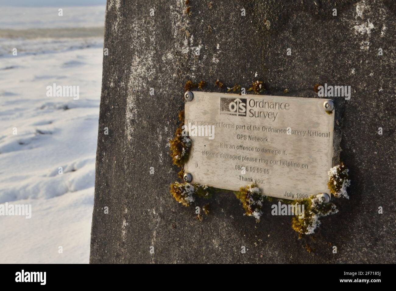 A plaque on a British Ordnance Survey trig point, stating that the trig point is part of the national GPS network, Scottish Highlands, UK. Stock Photo