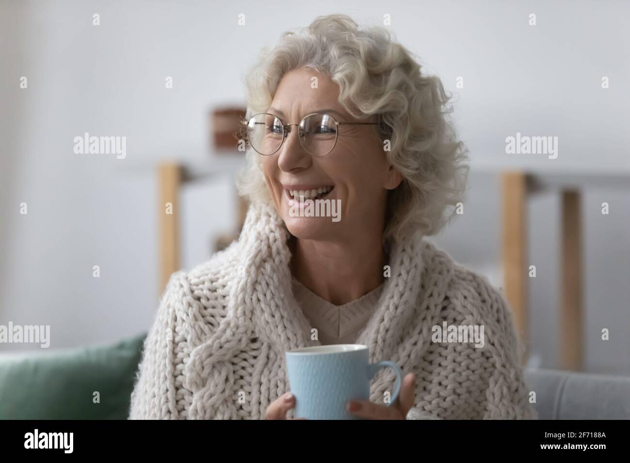 Happy mature 60s lady wrapped in plaid wearing glasses Stock Photo
