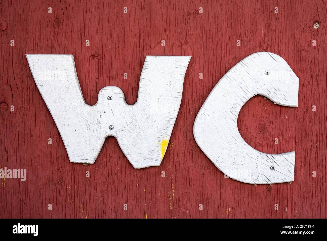 White WC letters on red ocher plywood door Stock Photo