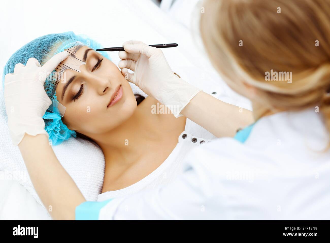 Professional beautician is going to correct eyebrow line at woman face ...