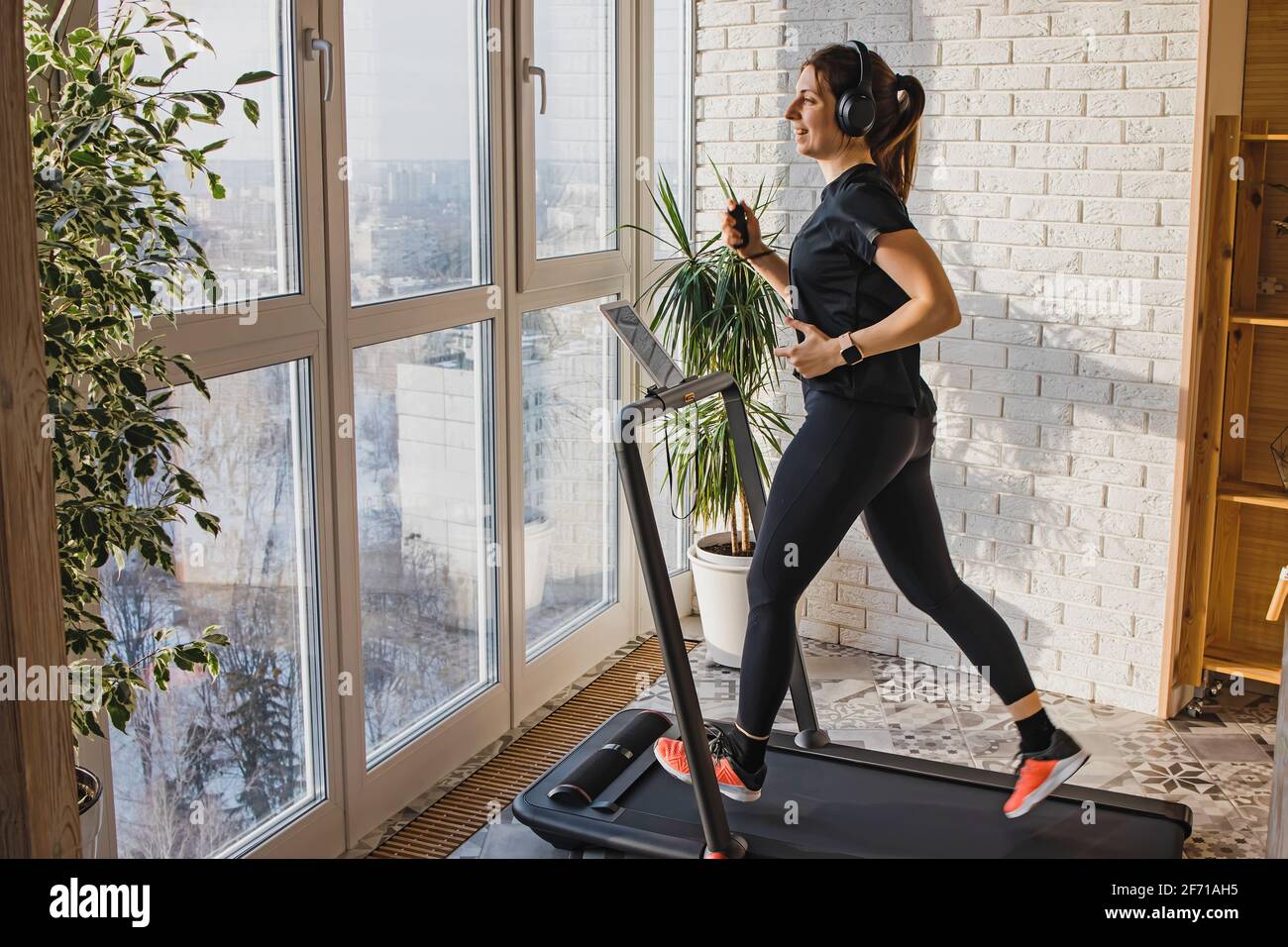 Woman jogging on the modern compact treadmill at her home Stock Photo