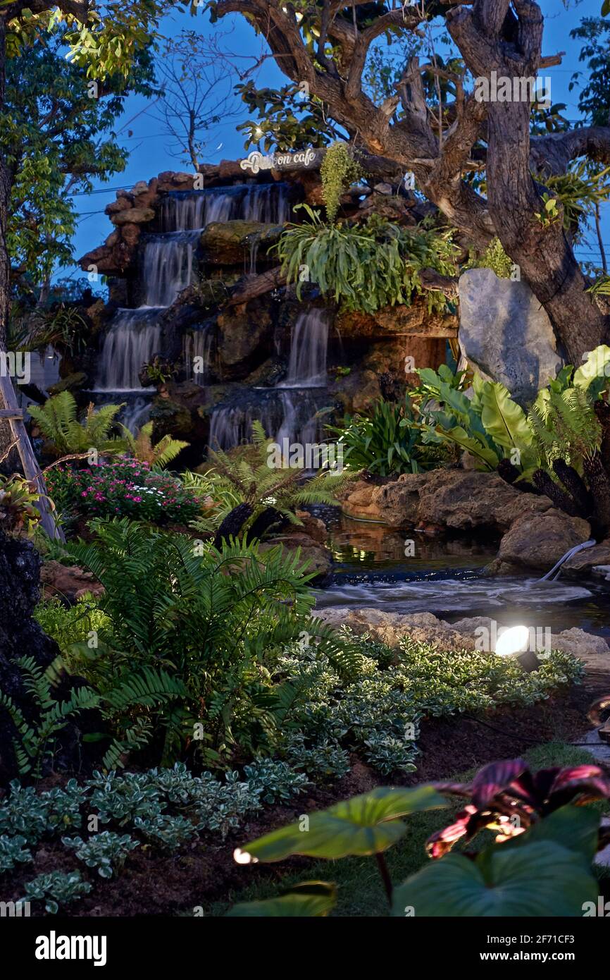 Fantasy garden with feature waterfall lit at night at a Thailand rural restaurant. Southeast Asia Stock Photo
