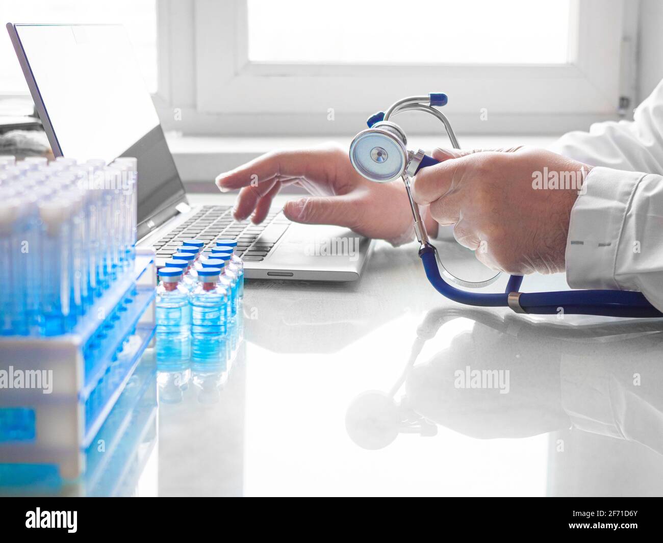 Vaccination medical research concept. Hands of a doctor working at a laptop. He fills out the patient's questionnaire online. Stock Photo