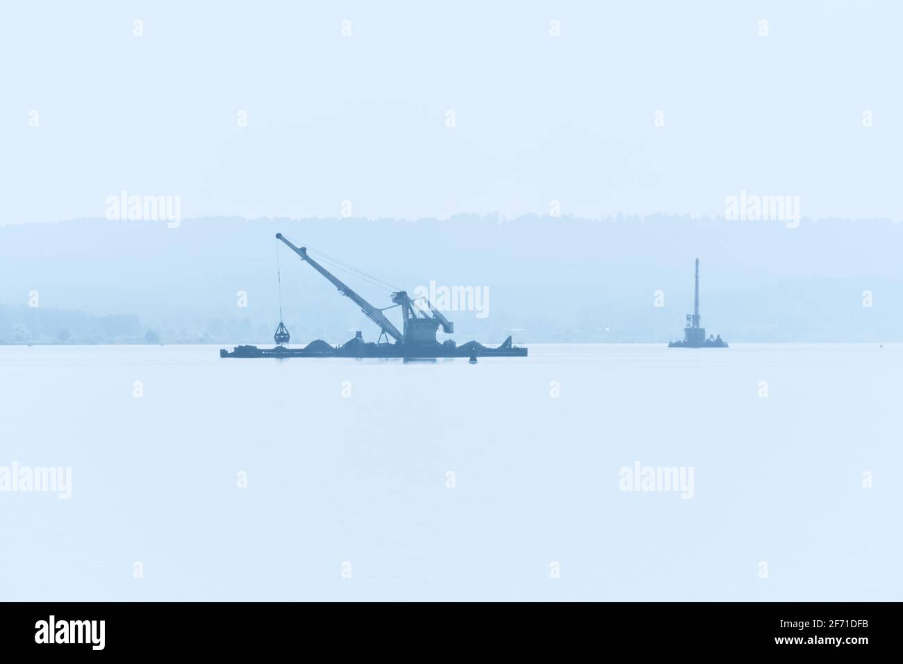 dredging boats is working to deepen the fairway on the river in the morning fog Stock Photo