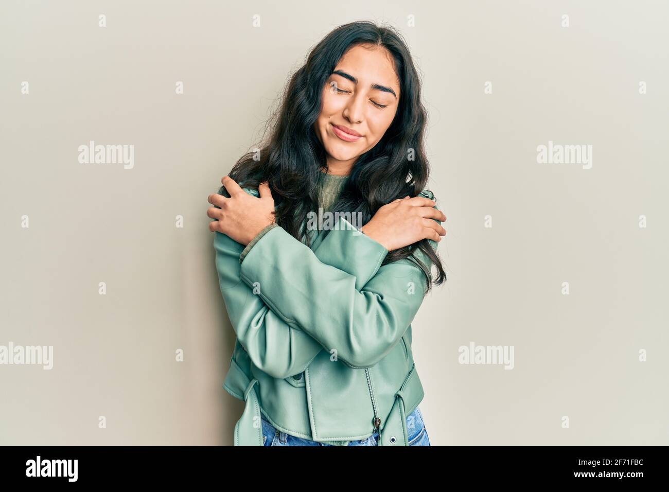 Hispanic teenager girl with dental braces wearing green leather jacket