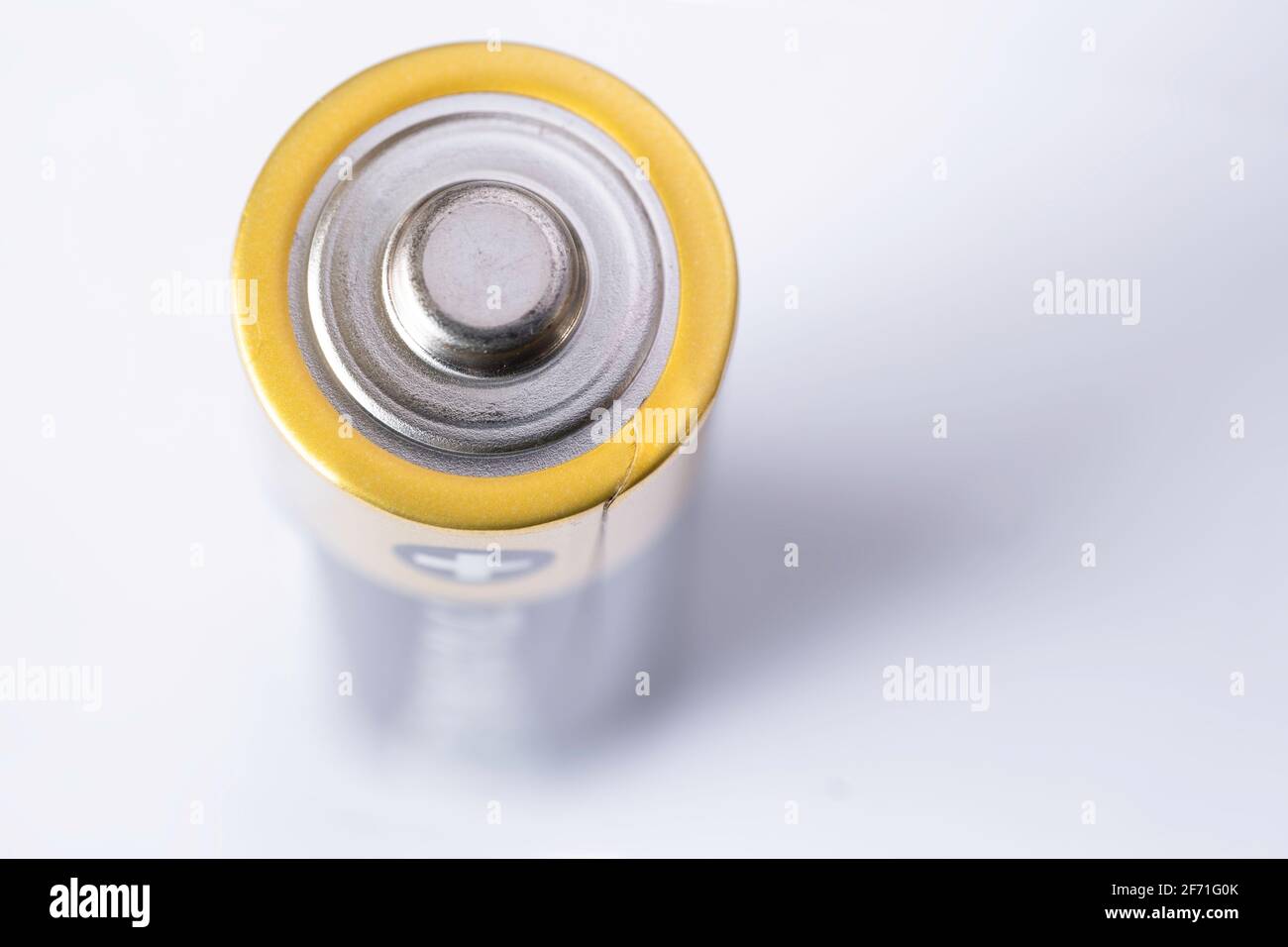 Closeup of an upright penlight battery on white with shadow, focus on