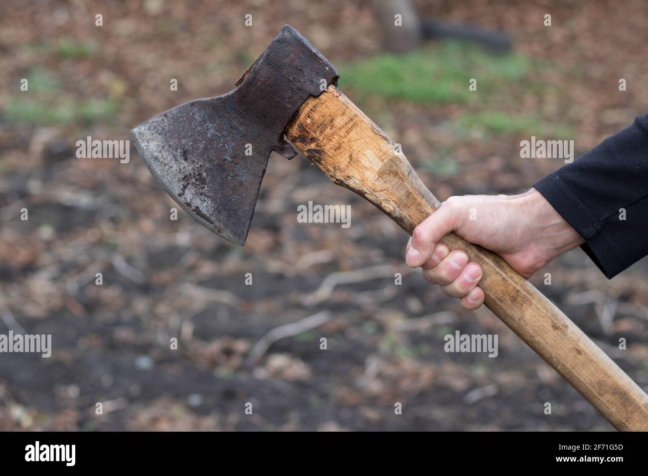 A man holds an ax in his hands against on black background. Stock Photo