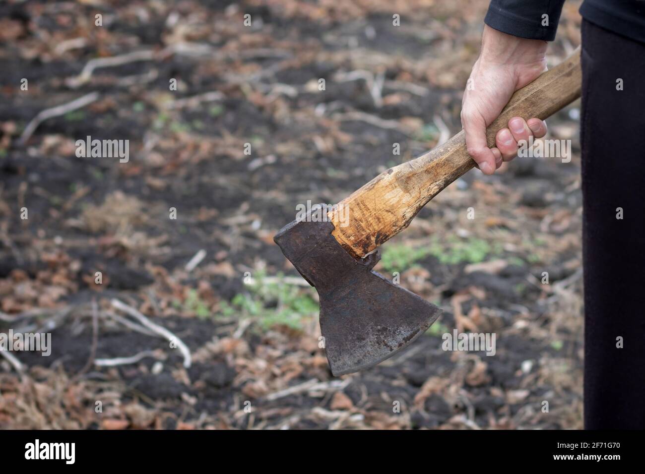 A man holds an ax in his hands against on black background. Stock Photo