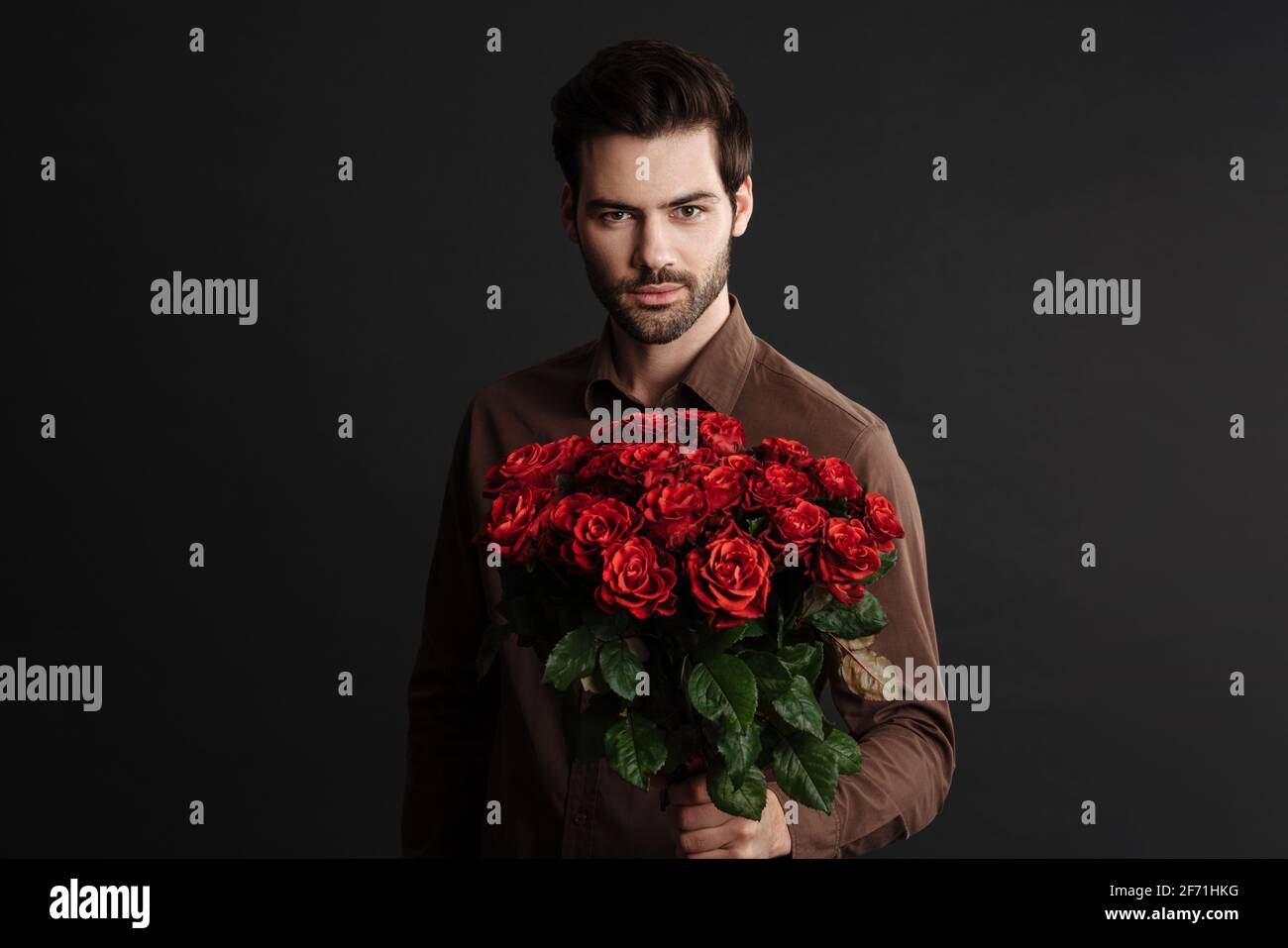 Confident handsome unshaven guy posing with bouquet of roses isolated ...