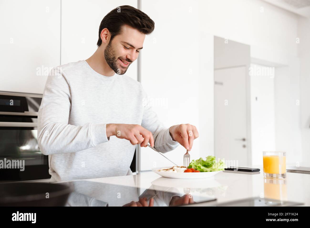 Happy handsome man smiling while having breakfast at home kitchen Stock Photo