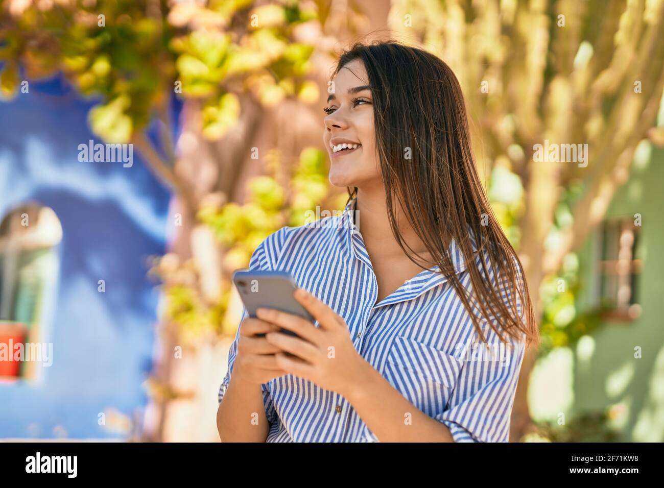 Young hispanic girl smiling happy using smartphone at the city Stock ...