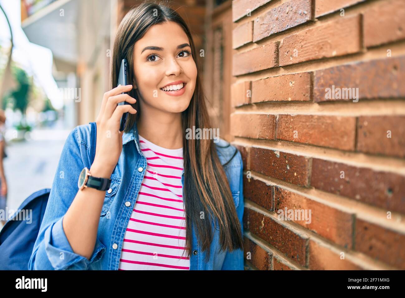 Young hispanic student girl smiling happy talking on the smartphone at ...