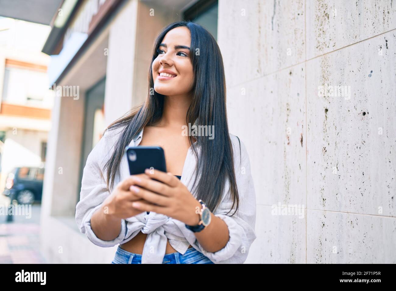 Young hispanic girl smiling happy using smartphone at the city Stock ...