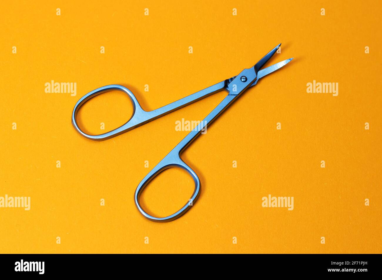 Small metal manicure scissors on yellow background. Stock Photo