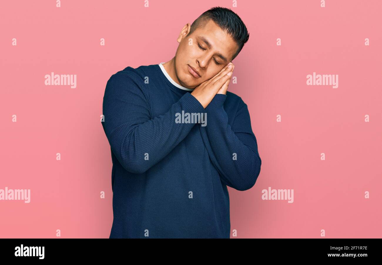Young latin man wearing casual clothes sleeping tired dreaming and ...