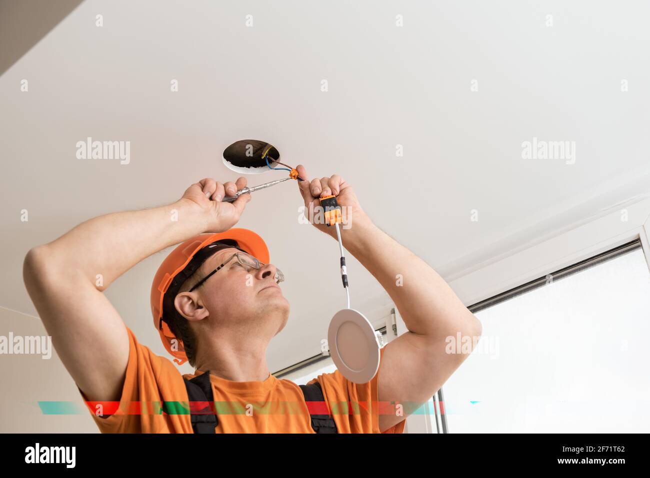 The electrician is installing an LED spotlight in the ceiling Stock ...