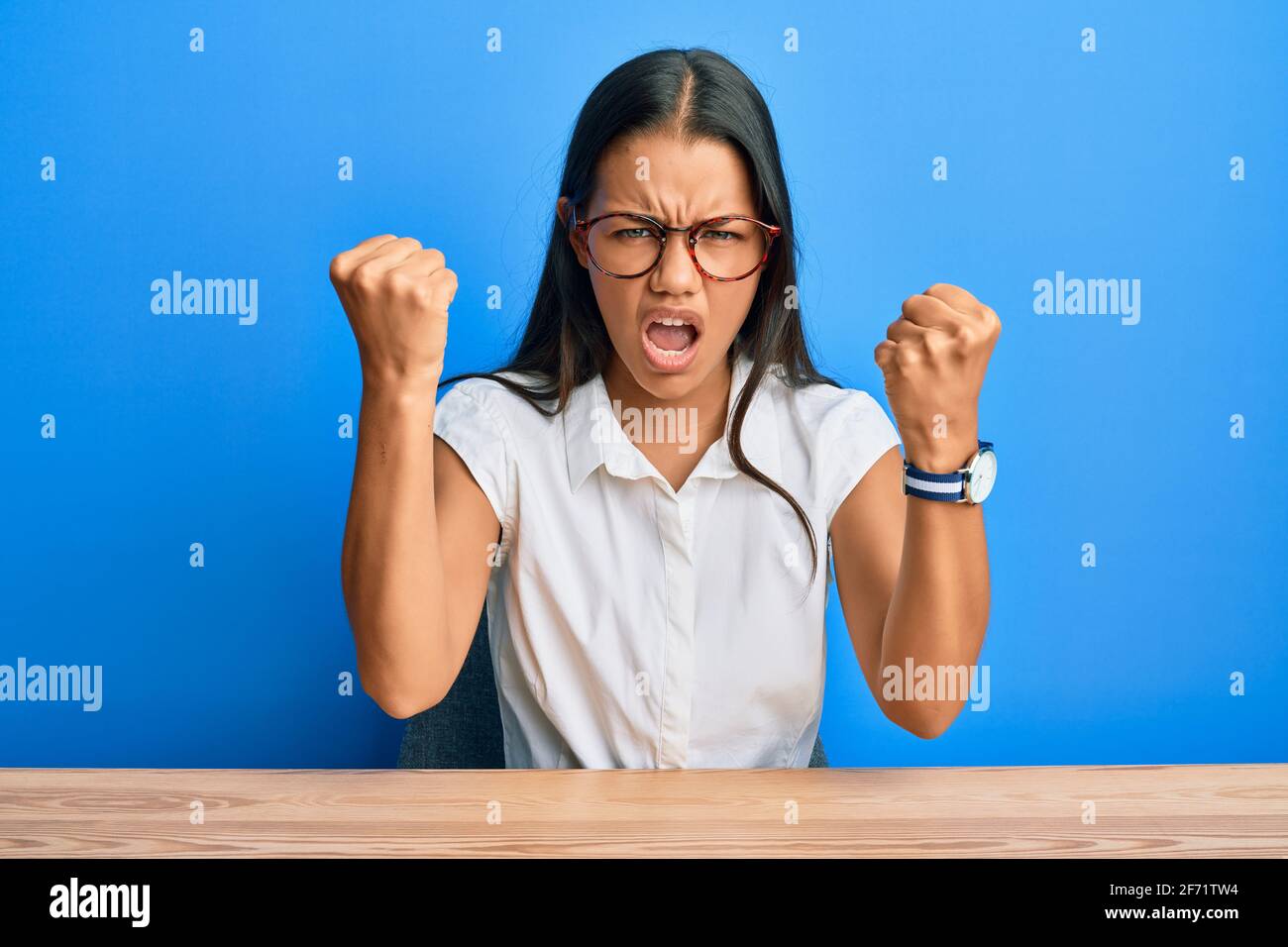 Beautiful hispanic woman wearing casual clothes sitting on the table ...