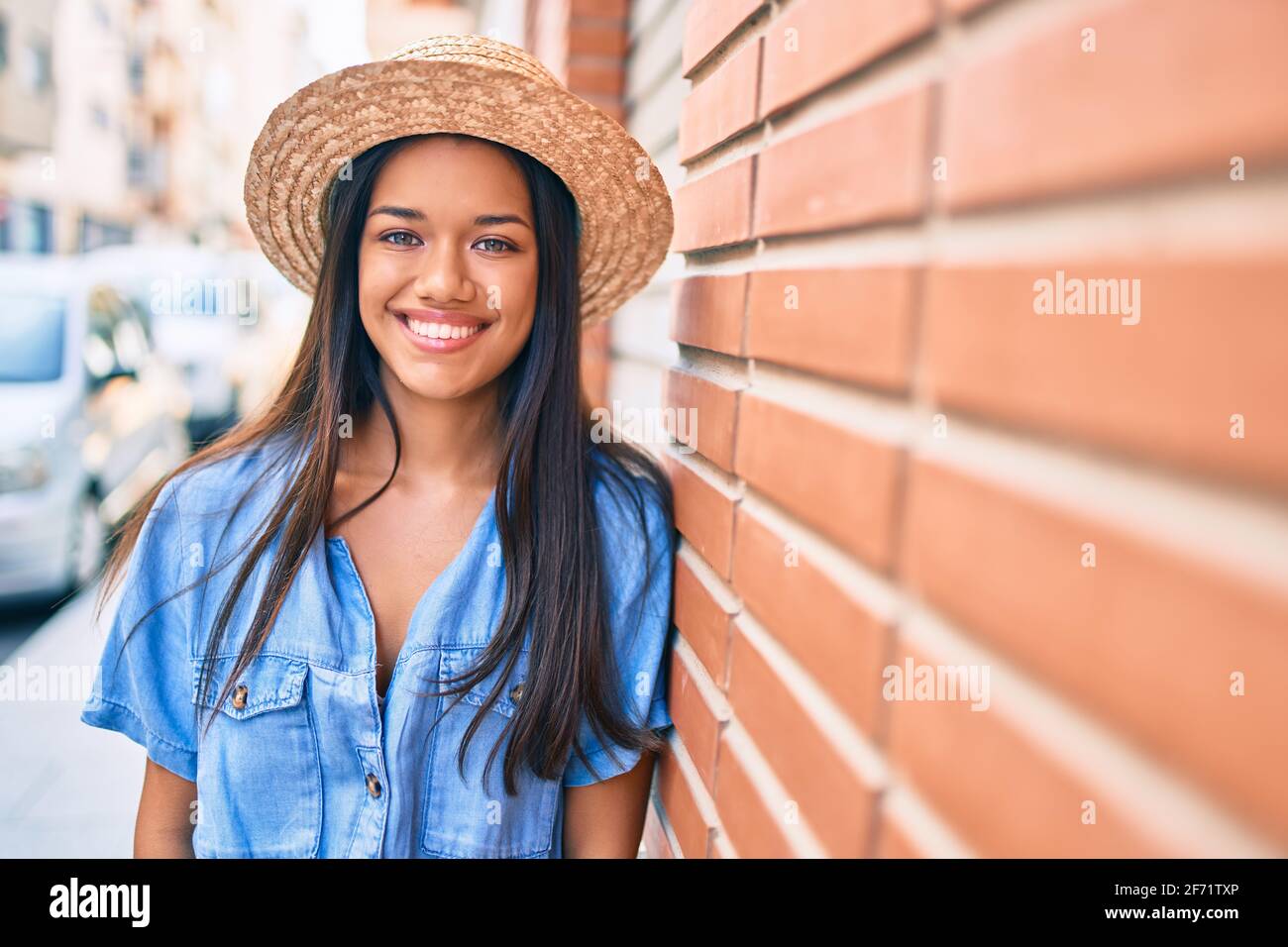 Young latin tourist girl on vacation smiling happy leaning on the wall ...