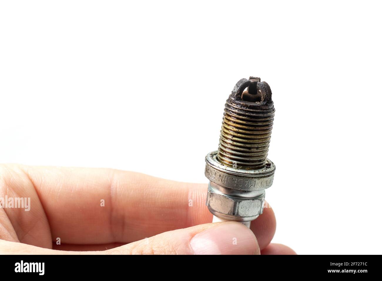 Dirty Lean Spark Plug. Auto mechanic holds an old spark plug on white