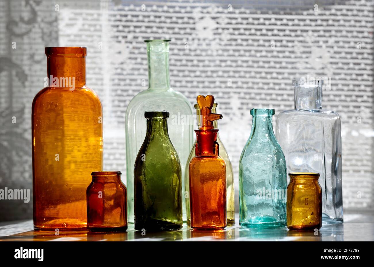 Antique glass bottles on a table next to a window Stock Photo