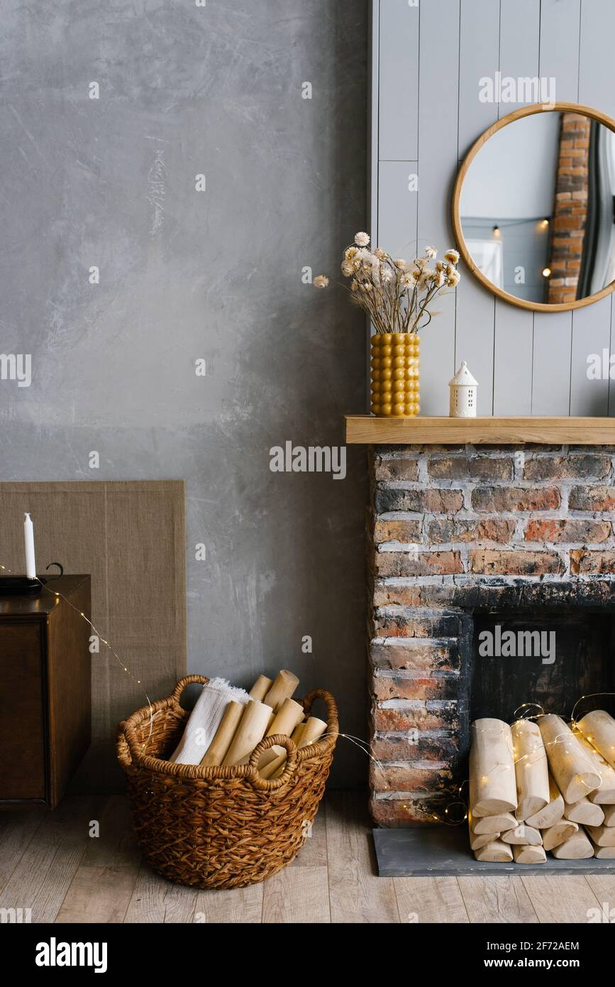 Scandinavian interior with red brick fireplace, wicker basket for firewood, pile of logs for a fire Stock Photo