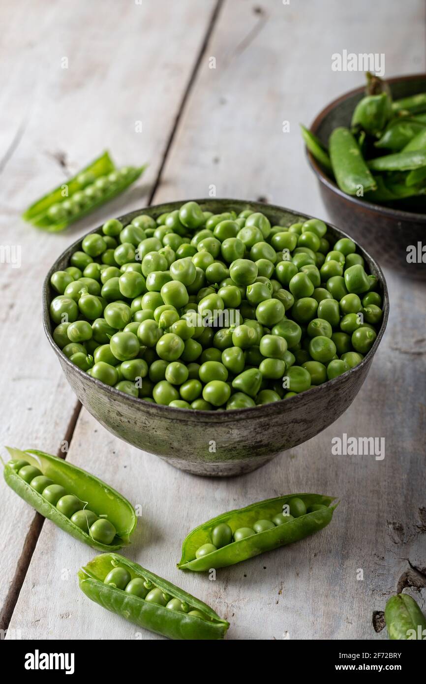 Fresh green peas. Fresh green peas pods and green peas in bowl on wooden background. Stock Photo