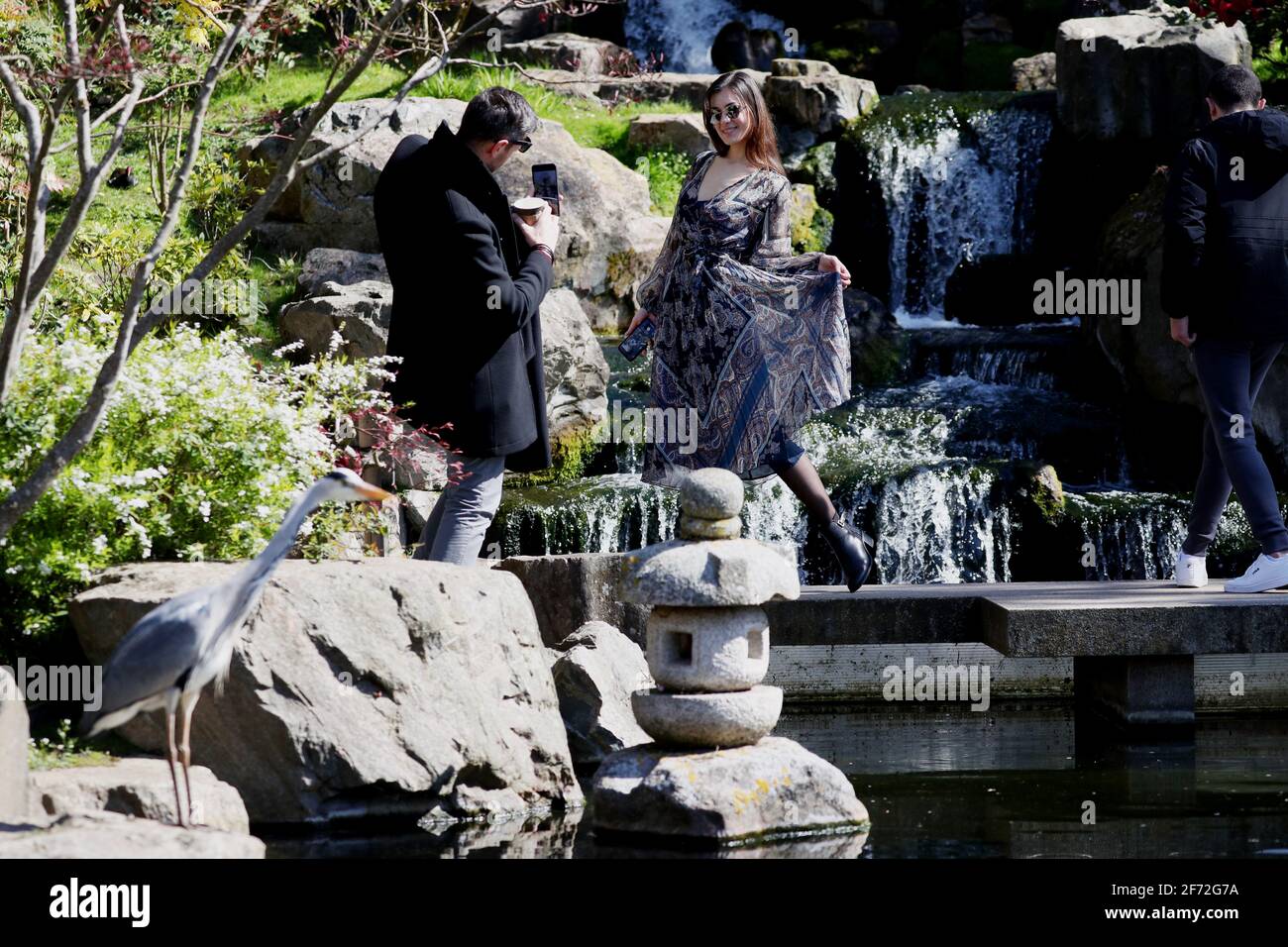 A woman poses for a photograph beside the waterfall in the Kyoto Garden ...