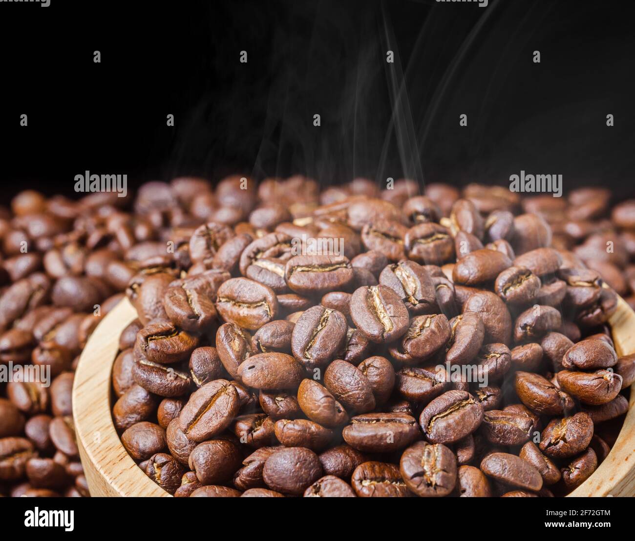 Coffee beans fresh roast with smoke on black background Stock Photo - Alamy