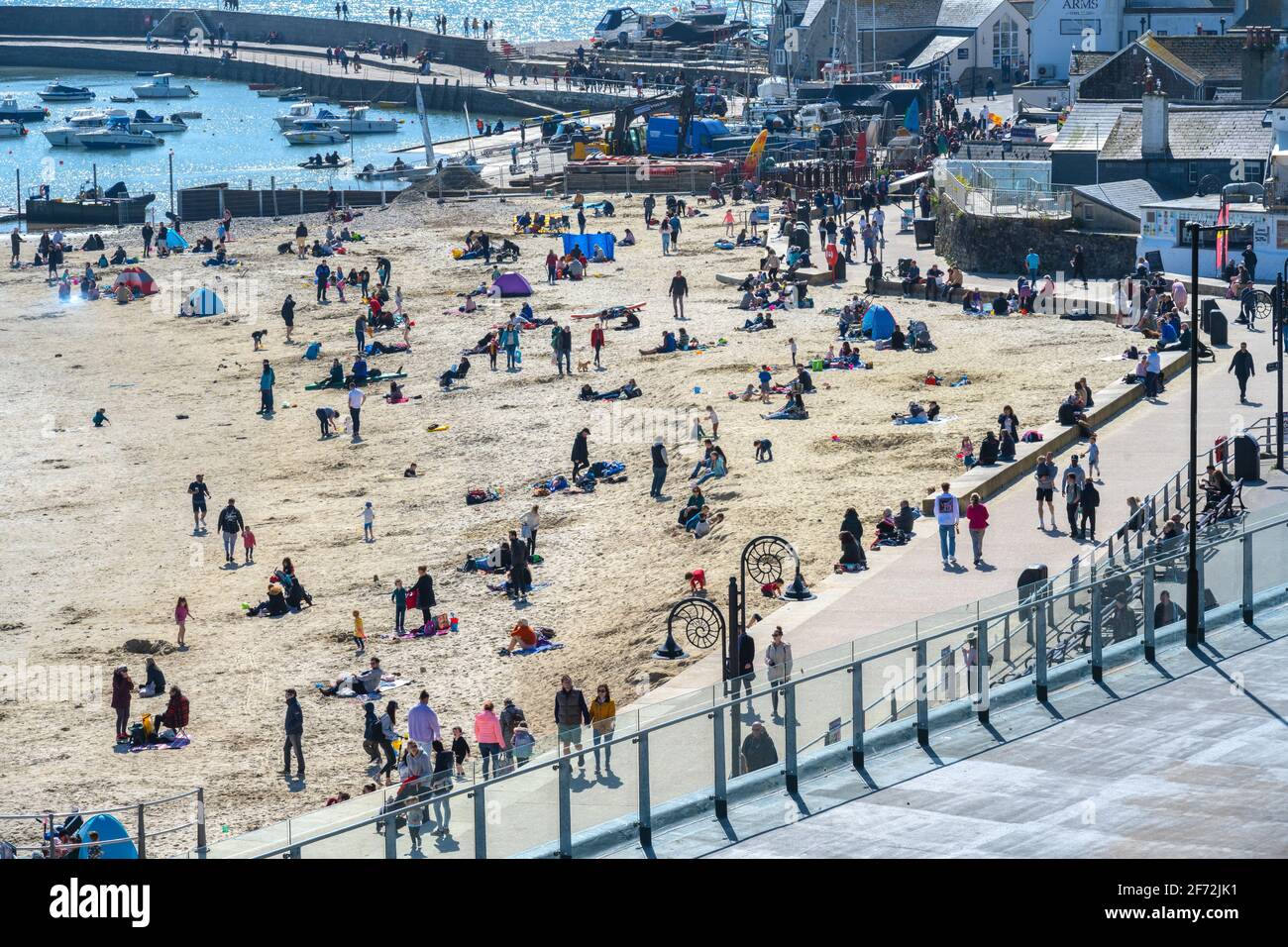 Lyme Regis, Dorset, UK. 4th Apr, 2021. UK Weather. Easter Sunday: Crowds flock to the pictureseque beach at the seaside resort of Lyme Regis on Easter Sunday Bank Holiday to make the best of the balmy sunshine and blue skies before temperatures plunge next week. Credit: Celia McMahon/Alamy Live News Stock Photo
