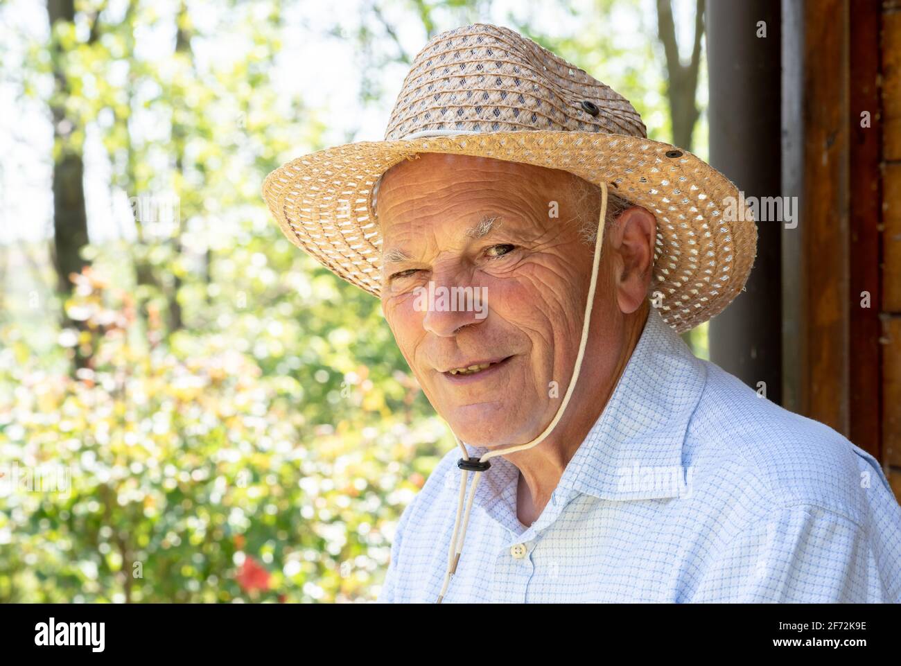Portrait of elderly smiling man with straw hat looking at the cam. Elderly people lifestyle Stock Photo