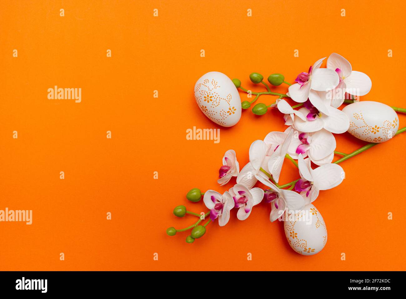 White Easter eggs and flowers on orange background. Spring holidays concept Stock Photo