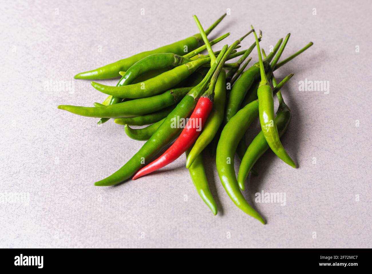 Slide of green chili peppers with one red on a light background. View ...