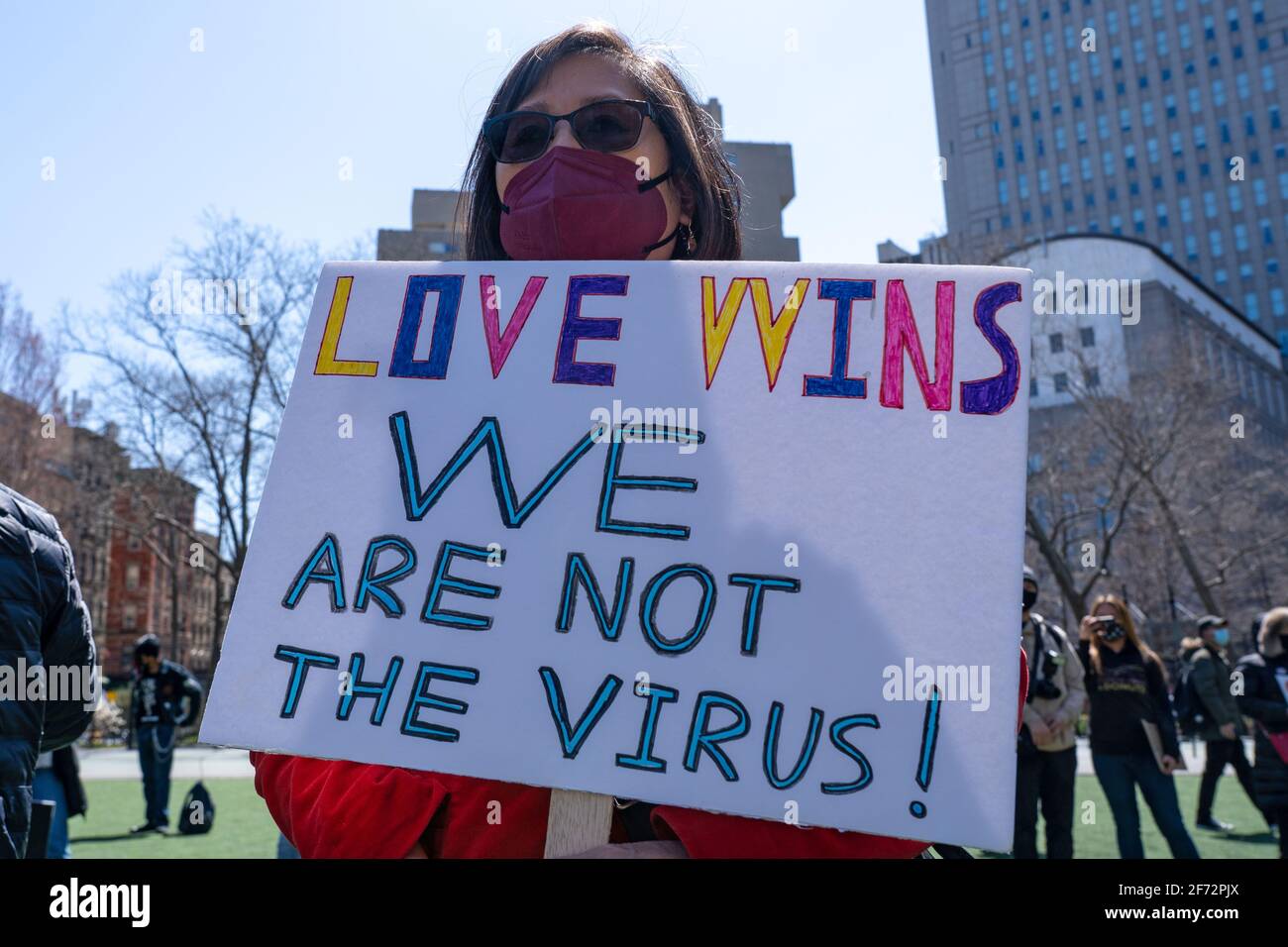 A woman holds a sign that reads 'love wins we are not the virus!' at a rally against hate in Columbus Park.A rally for solidarity was organized in response to a rise in hate crimes against the Asian community since the start of the coronavirus (COVID-19) pandemic in 2020. On March 16 in Atlanta, Georgia, a man went on a shooting spree in three spas that left eight people dead, including six Asian women. Stock Photo