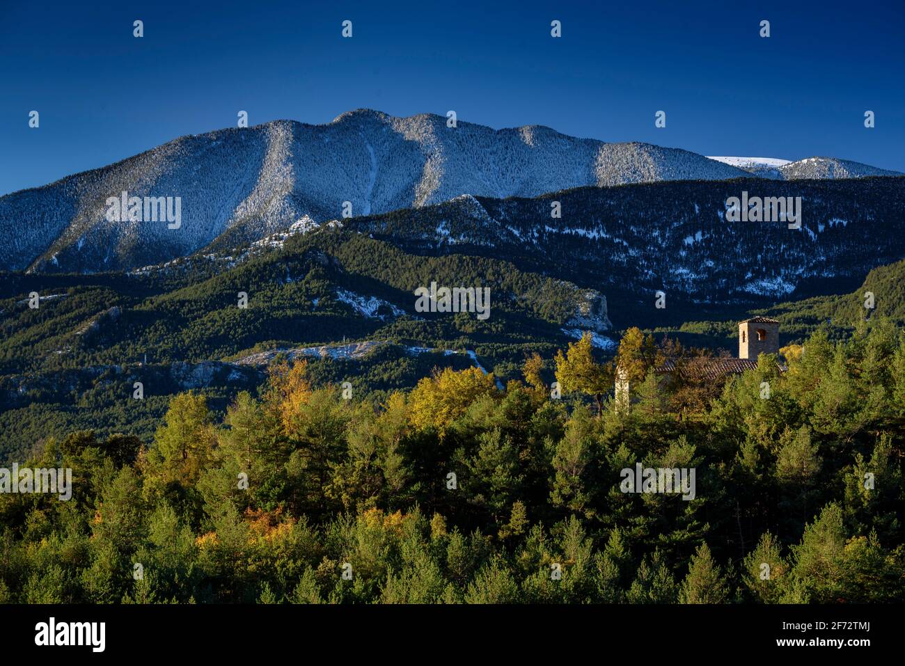 Serra d'Ensija range and Sant Miquel de Turbians church, in autumn, after a snowfall. Seen from near to Albert Arilla viewpoint, in Gisclareny (Spain) Stock Photo