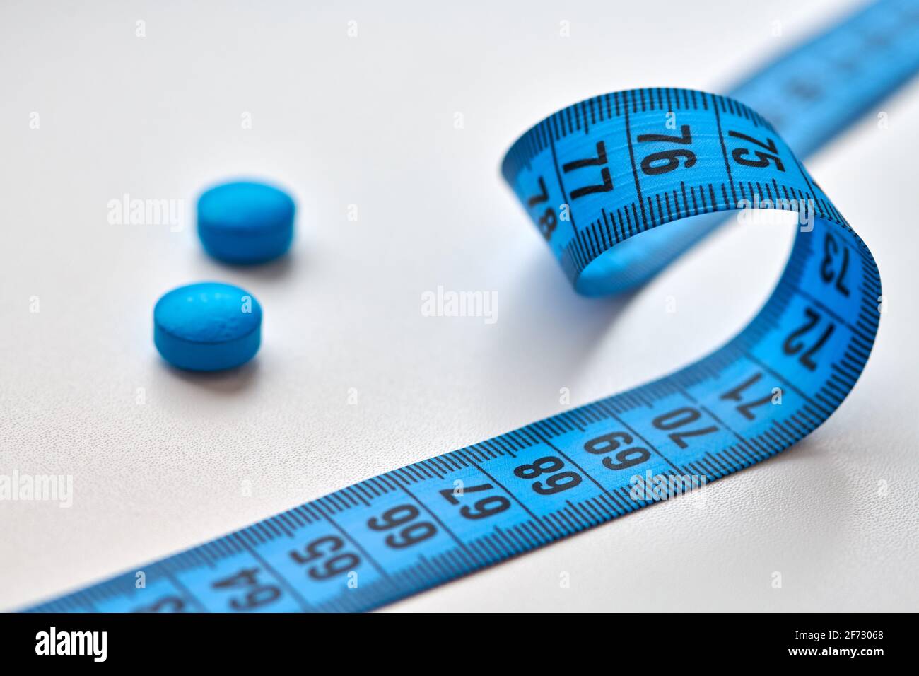 Blue round diet pills and measuring centimeter tape isolated on