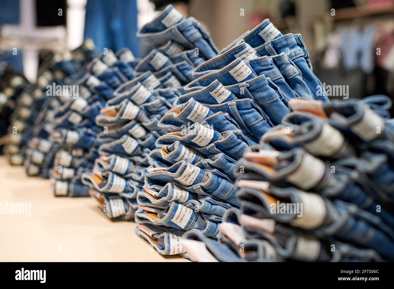 Blue denim jeans stack on wooden table 