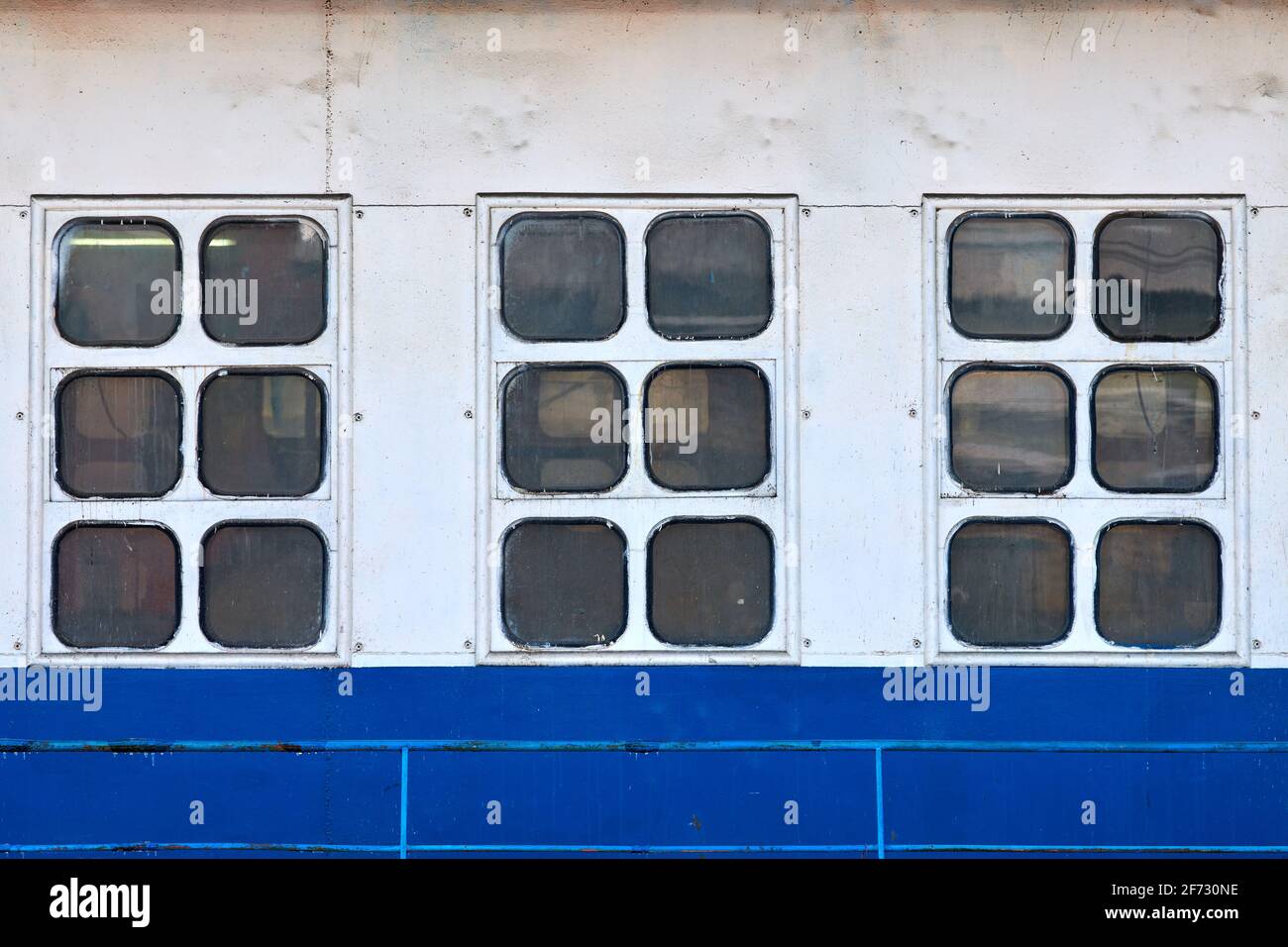 Three cabin windows and portholes on outboard side of ship. Close up of