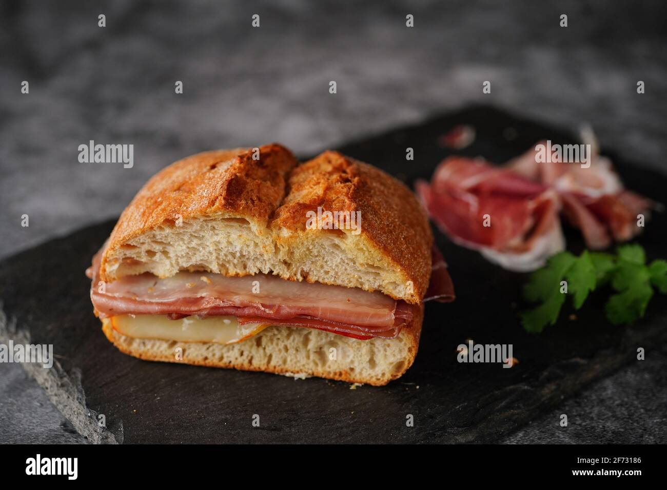 Simple Prosciutto ciabatta sandwich on dark moody setting Stock Photo