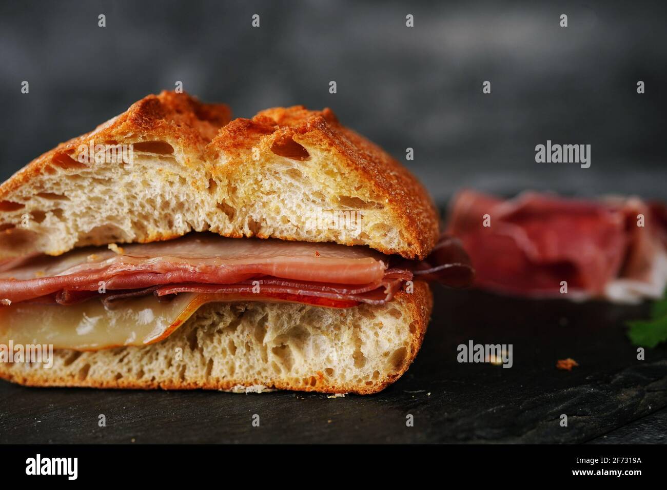 Simple Prosciutto ciabatta sandwich on dark moody setting Stock Photo