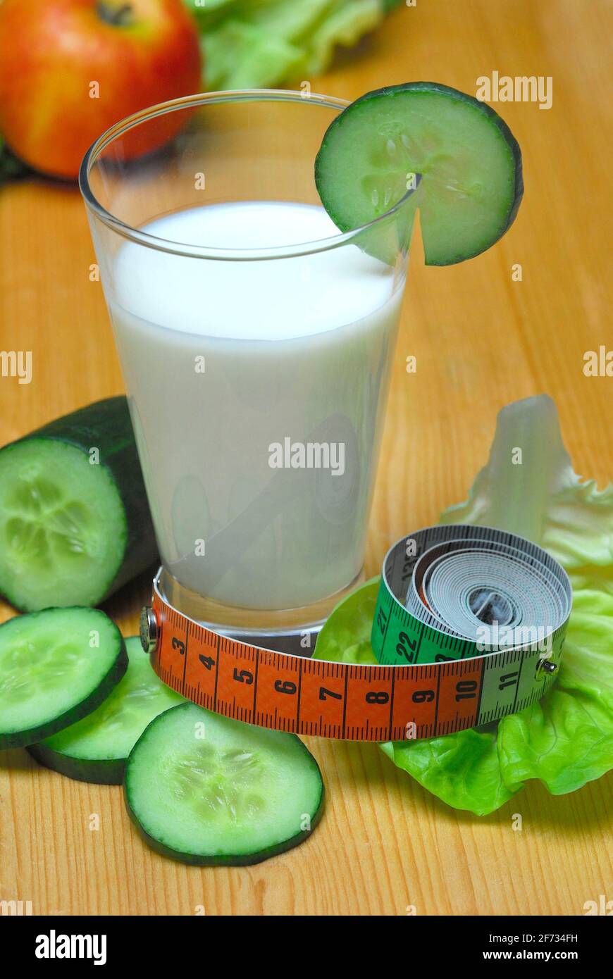 Glass of buttermilk, cucumber, lettuce leaf, milk, straw, lettuce, lettuce, cucumber, measuring tape Stock Photo