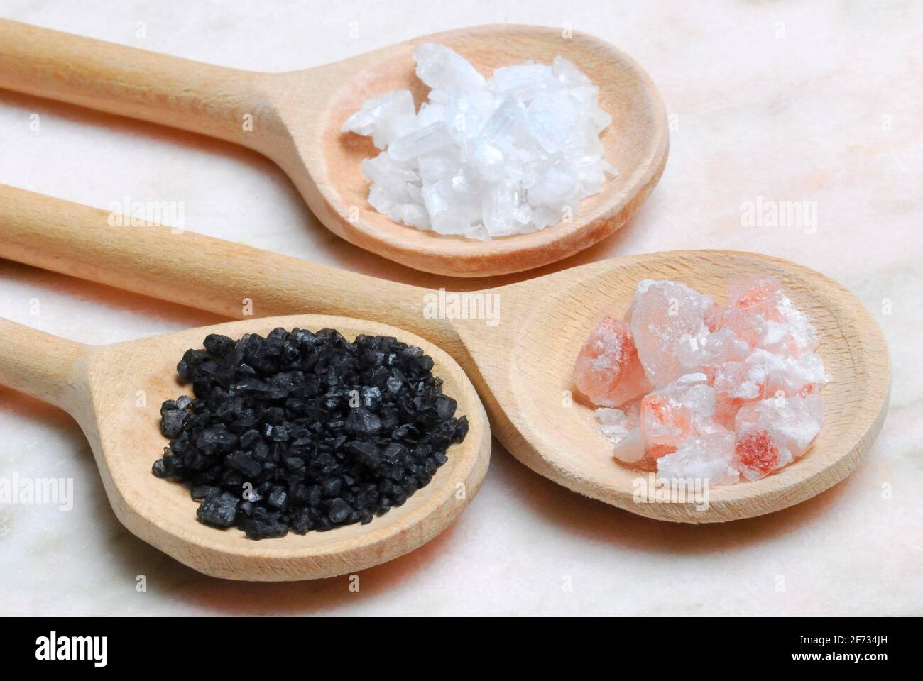 Different kinds of salt on wooden spoons, crystal salt, Himalayan salt, Hawaiian salt, sodium