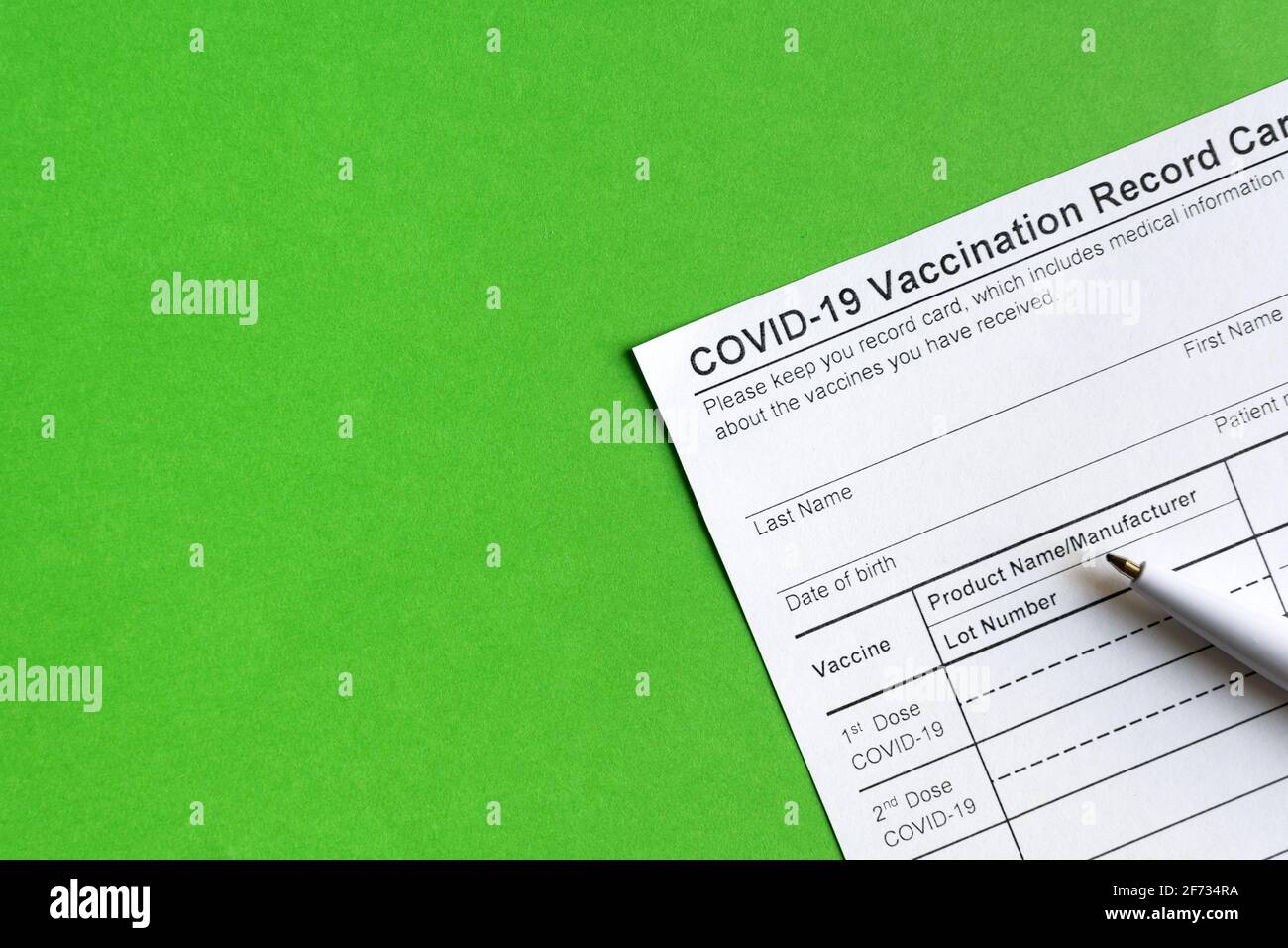COVID-19 Vaccination Record Card on green background, coronavirus immunization certificate with copy space. Top view of paper medical form required fo Stock Photo