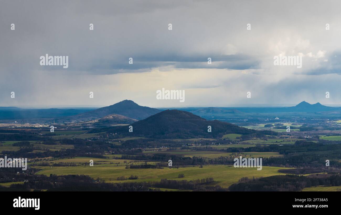 scenic view of Mount Ralsko and Mount Tlustek in the Bohemian Lusatian Mountains as seen from Mount Hochwald in Germany with storm clouds and rain plu Stock Photo