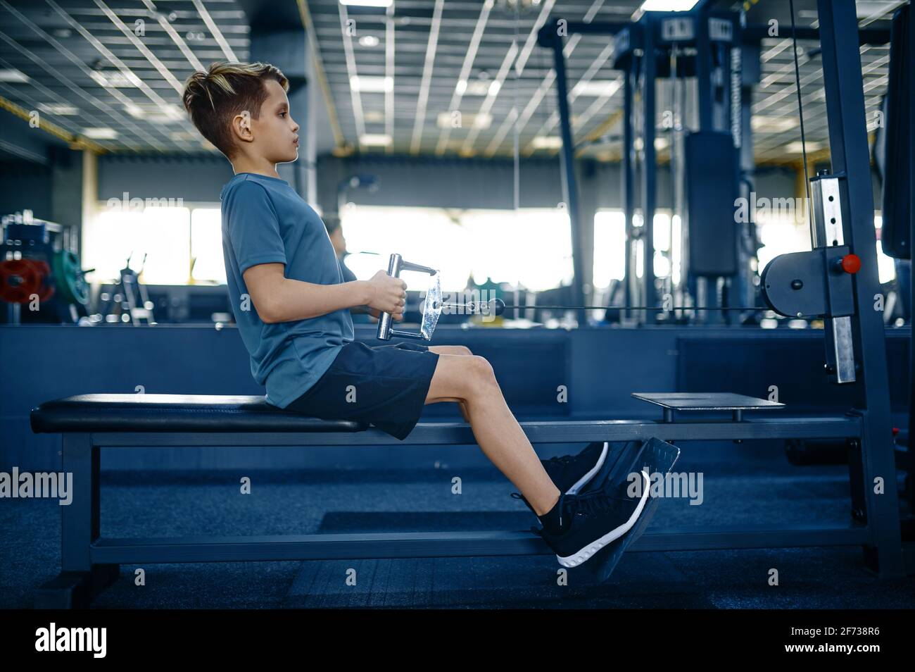 Boy on exercise machine, training in gym Stock Photo Alamy