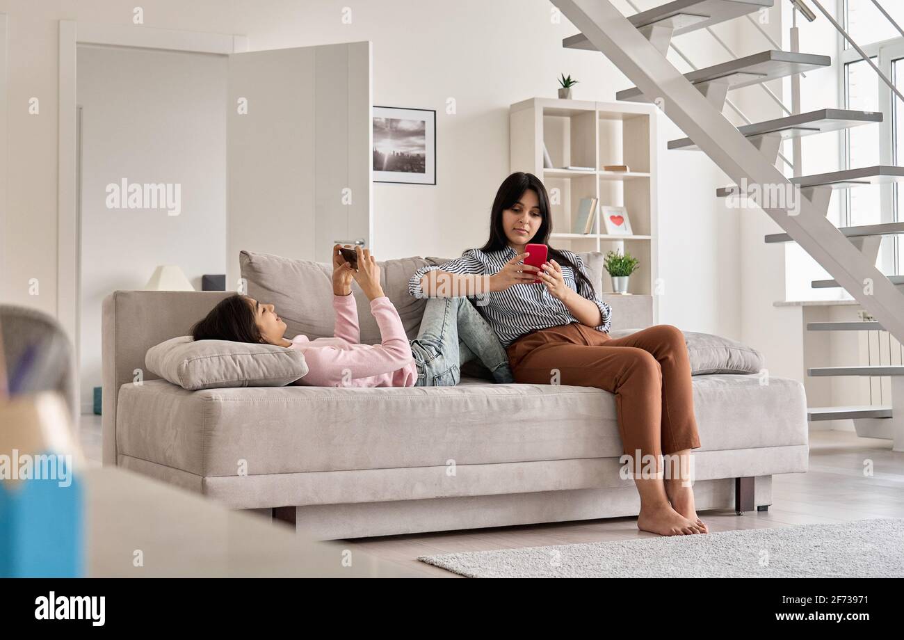 Indian family mother with teen daughter using phones devices at home. Stock Photo