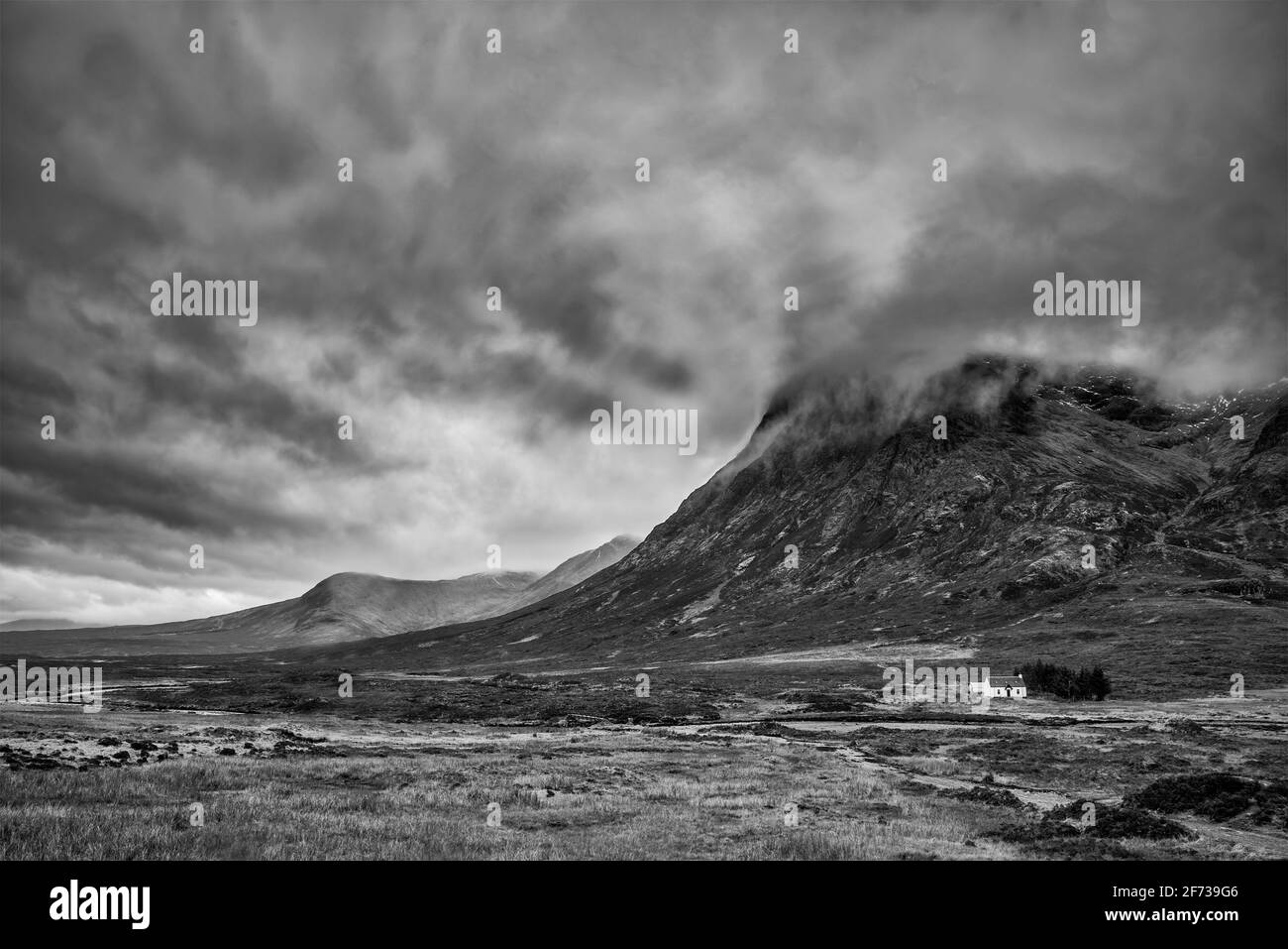 Stunning  black and white landscape image view down Glencoe Valley in Scottish Highlands with mountain ranges in dramatic Winter lighting Stock Photo