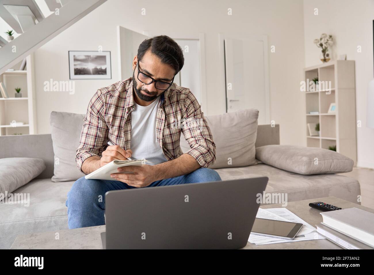 Indian man working or studying online from home office using laptop computer. Stock Photo