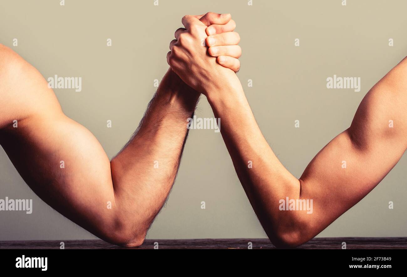 Arm wrestling thin hand and a big strong arm in studio. Two man's hands